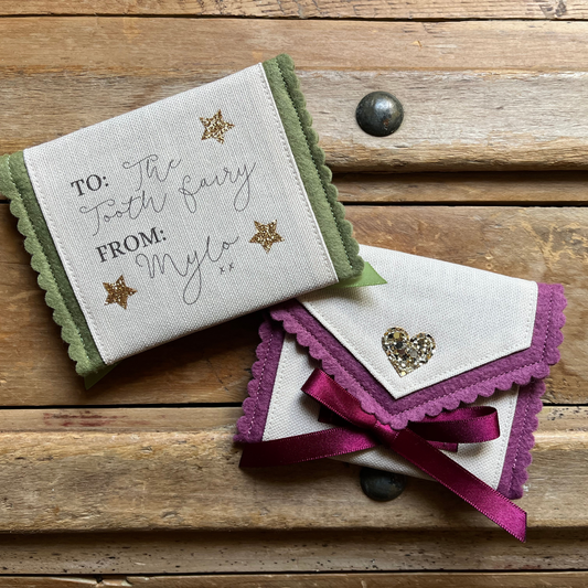 Decorative tooth fairy pouch with personalised text and star designs on a wooden surface