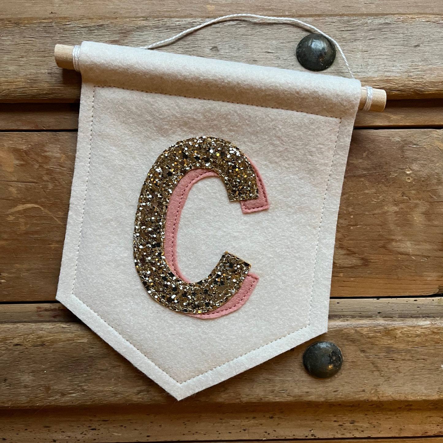 Cream felt initial banner with chunky gold glitter and pink drop shadow effect perfect for kids room decor