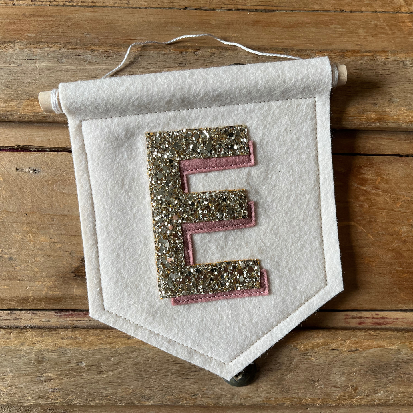 Cream felt initial banner with chunky gold glitter and pink drop shadow effect perfect for kids room decor