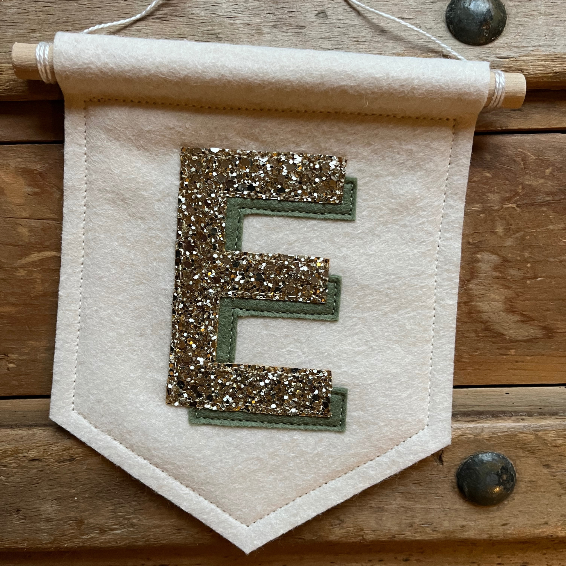 Cream felt initial banner with chunky gold glitter and sage green drop shadow effect perfect for kids room decor