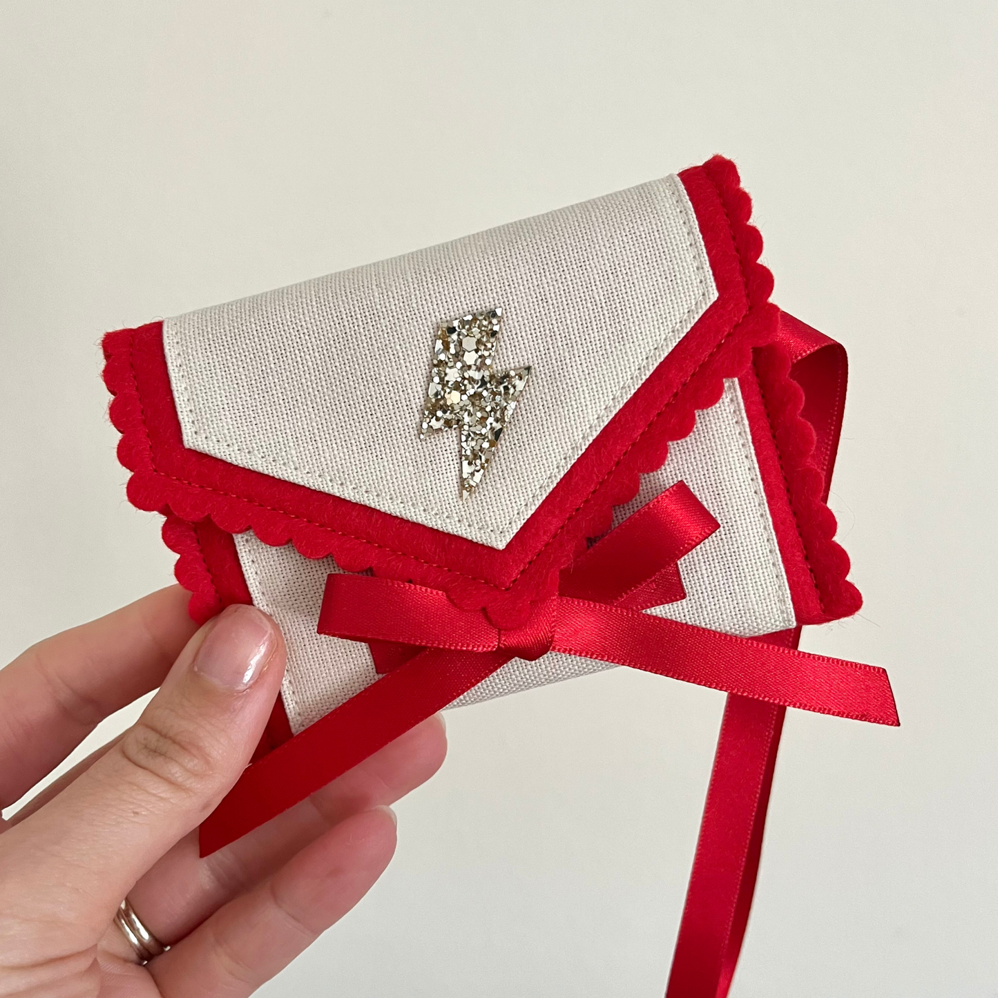 Decorative personalised tooth fairy pouch with glitter detail, ribbon fastening and scalloped edging. 